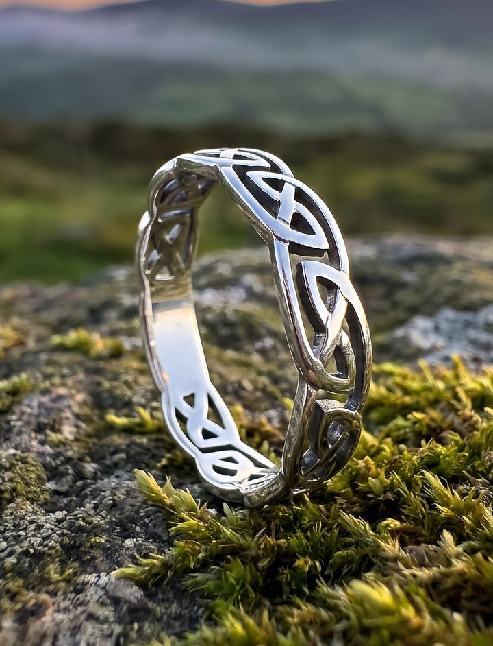 Étaíns Band: keltischer Ehering aus 925 Silber mit geflochtenem Knotenband auf Moosstein über nebligen irischen Hügeln