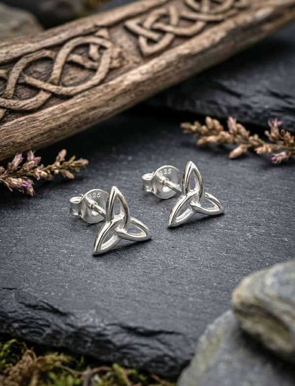 Keltische Triquetra Ohrstecker aus 925 Silber auf Schiefer vor keltischer Holzschnitzerei