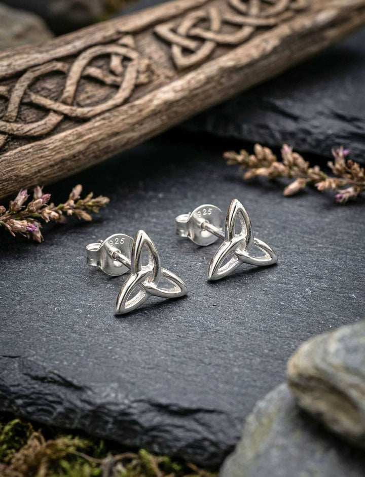 Keltische Triquetra Ohrstecker aus 925 Silber auf Schiefer vor keltischer Holzschnitzerei