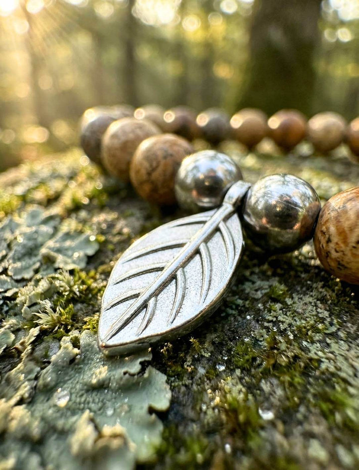 Edelstahl-Blatt Detail zwischen Holzperlen auf Moos im Waldlicht