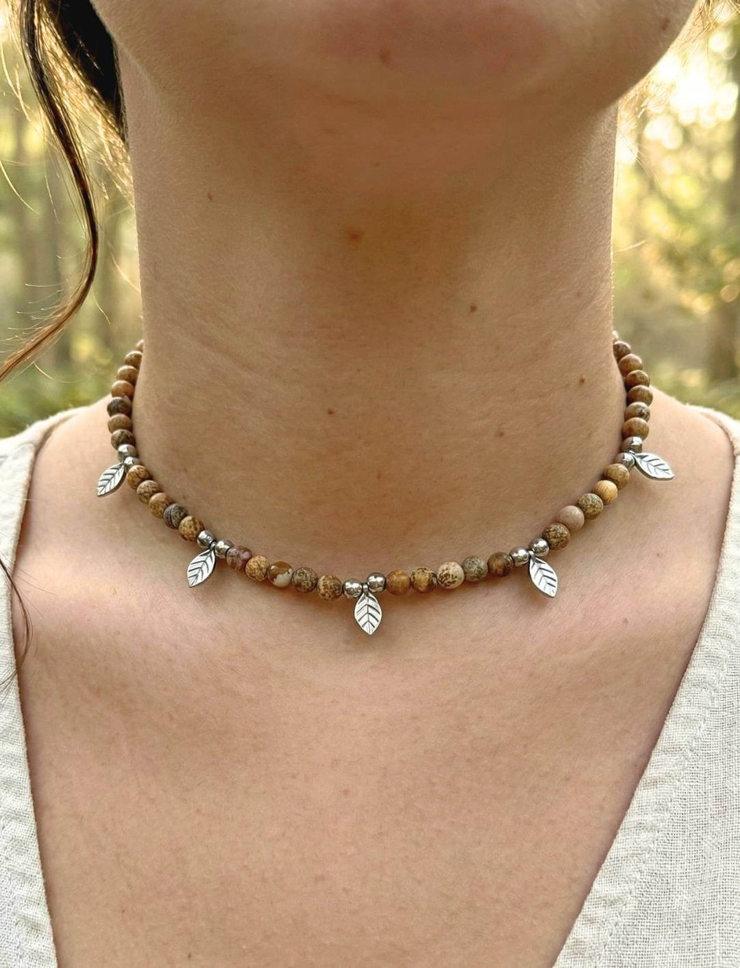 Frau trägt handgefertigten Holzperlen Choker mit Edelstahl-Blättern im Wald