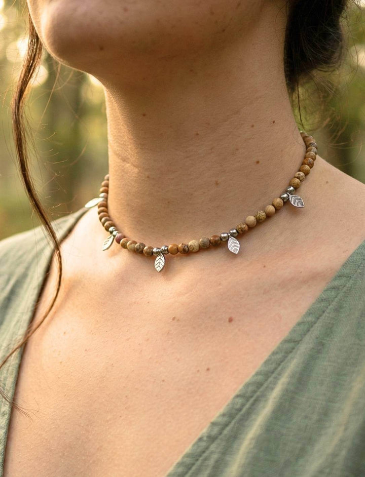 Frau in grüner Tunika trägt handgefertigten Holzperlen Choker mit Edelstahl-Blättern