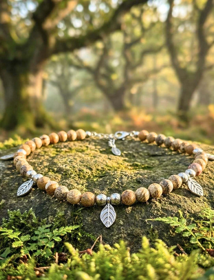 Handgefertigter Choker mit Holzperlen und Blättern auf moosbedecktem Stein im Hain