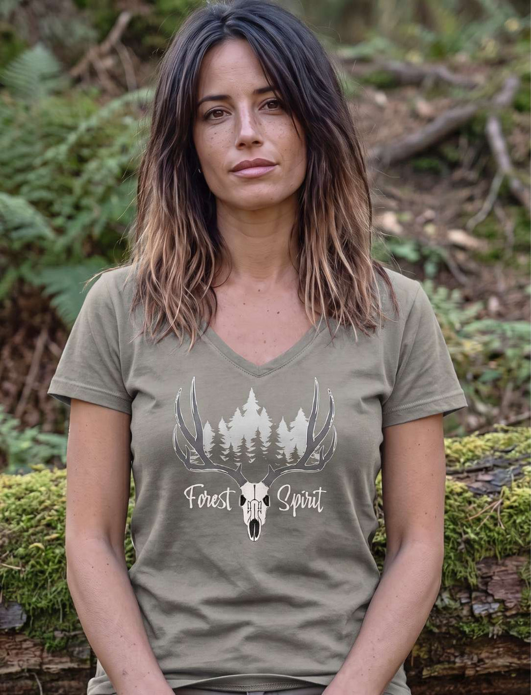 Frau im hellgrauen Damenshirt mit Waldmotiv, sitzend auf einem bemoosten Stamm