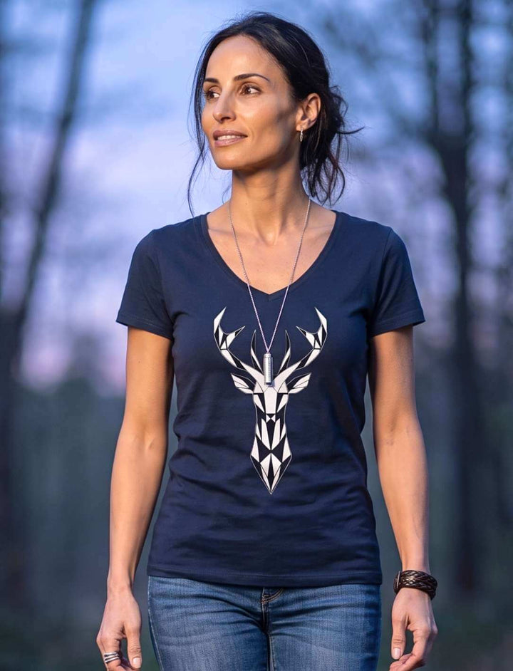 Frau im dunkelblauen Shirt mit Hirschkopf zwischen kahlen Bäumen