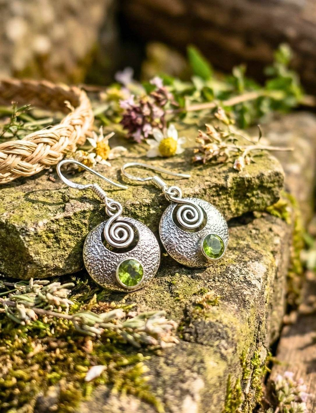 Silberohrringe mit Peridot und keltischer Spirale auf moosbedecktem Stein im Grünen