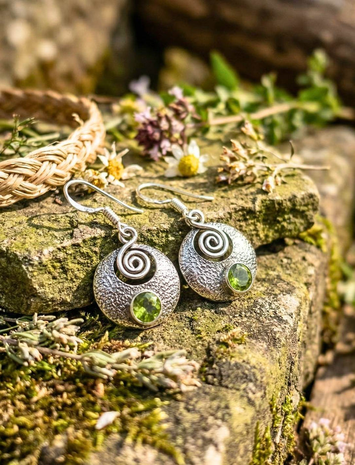 Silberohrringe mit Peridot und keltischer Spirale auf moosbedecktem Stein im Grünen