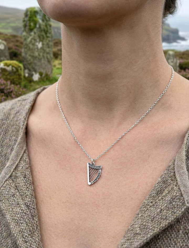 Frau trägt irische Harfe Anhänger aus 925 Silber an Kette vor irischer Küste