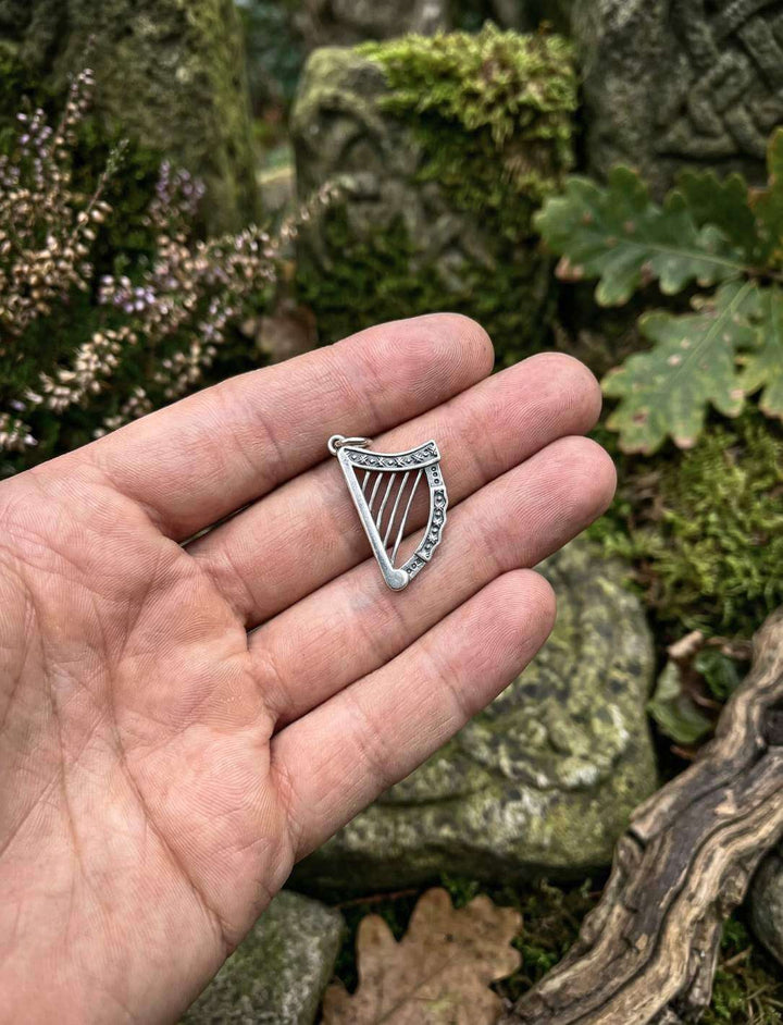 Hand hält irische Harfe Anhänger aus 925 Silber Größenvergleich im Wald