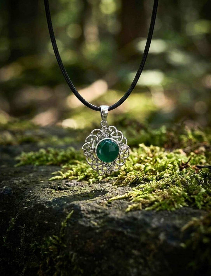 Irischer Shamrock-Anhänger mit grünem Achat an schwarzer Lederkette auf moosigem Stein im Wald