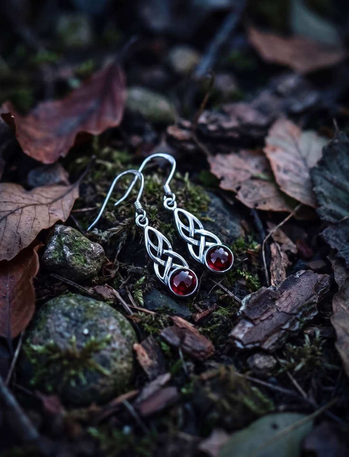 Silber Ohrhänger mit Granat auf feuchtem Waldboden zwischen Laub und Steinen