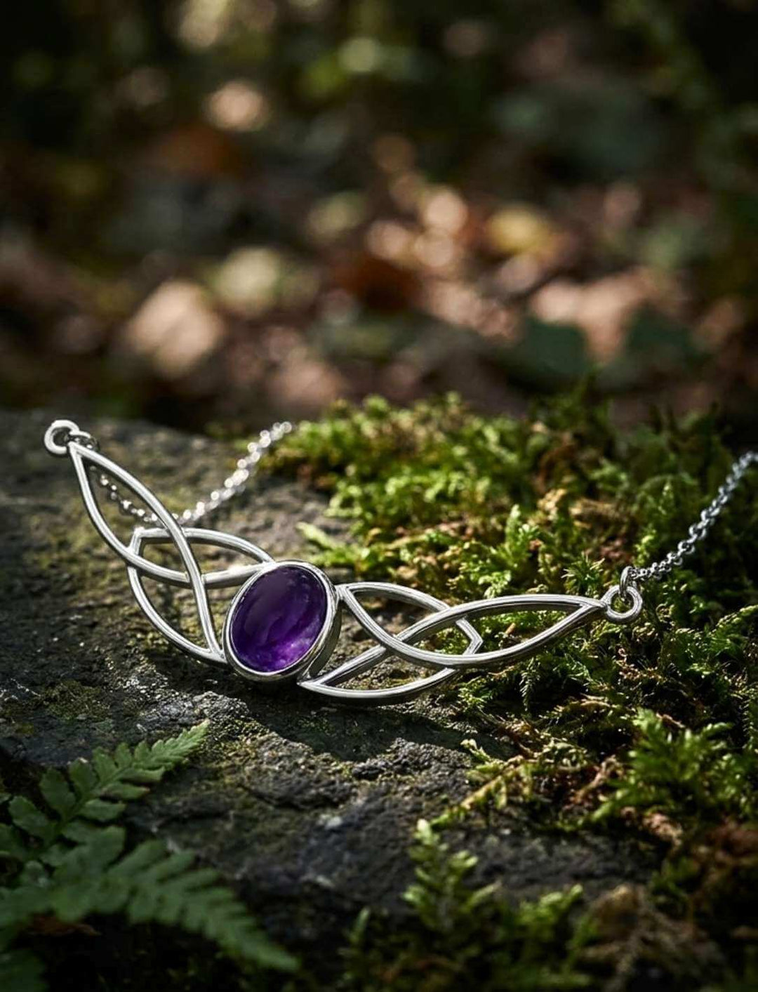 Keltischer Knoten-Charm mit violettem Amethyst auf bemostem Stein