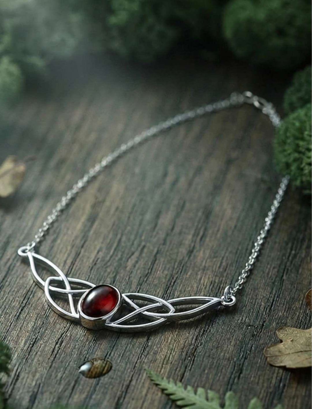Keltische Knotenkette mit Granat in 925 Sterling Silber auf dunklem Holz
