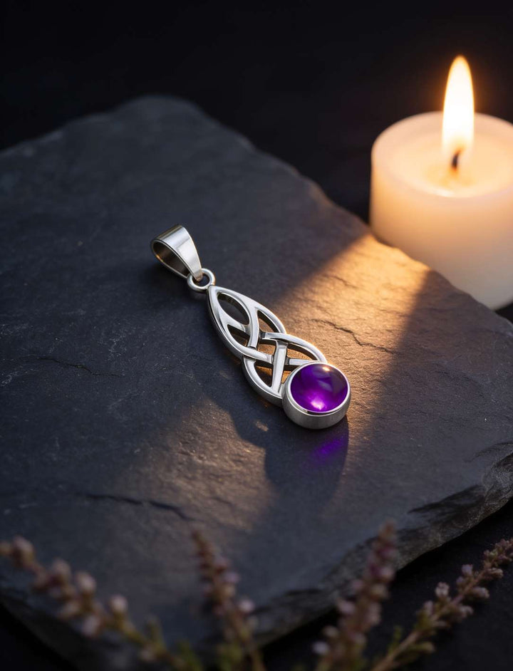 Detailaufnahme des keltischen Knotenmusters und des runden Amethyst-Cabochons neben einer Kerze