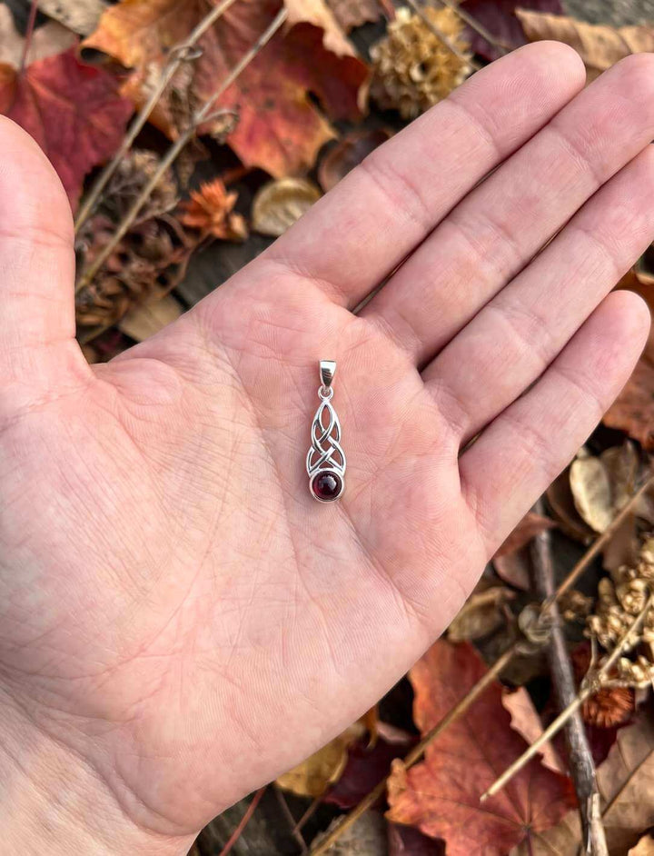 Granat Anhänger in der Hand, Größenvergleich im Herbstlaub