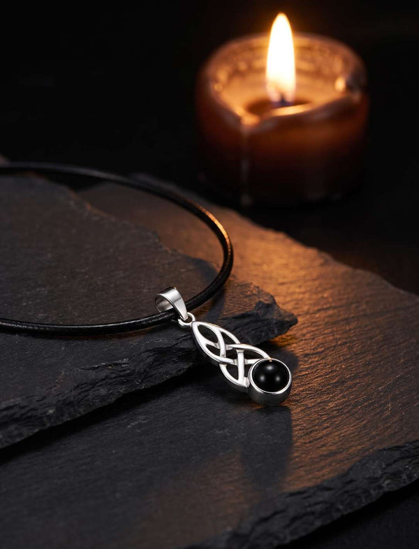 Keltischer Knoten Anhänger mit Onyx am Lederband bei warmem Kerzenlicht