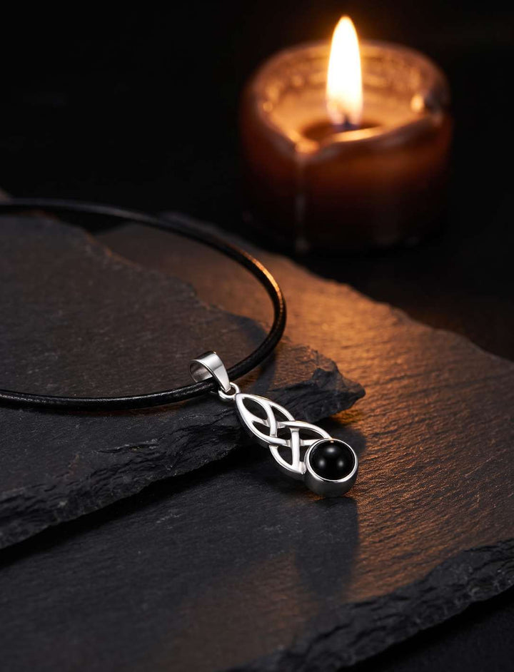 Keltischer Knoten Anhänger mit Onyx am Lederband bei Kerzenlicht
