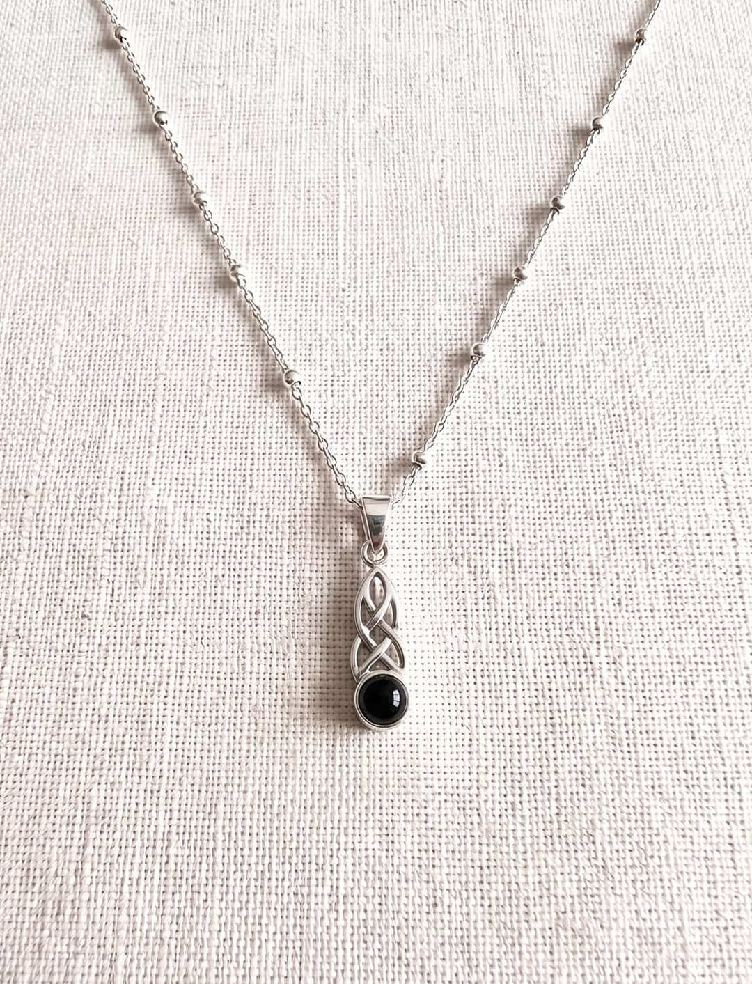 Silberkette mit Onyx Anhänger auf hellem Stoff