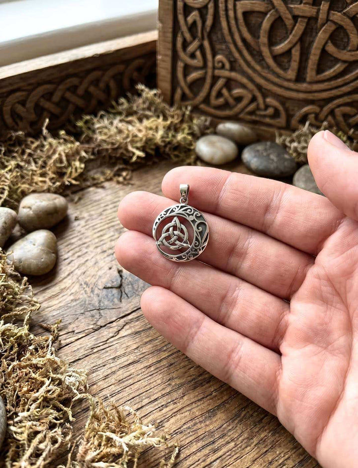 Keltischer Knoten Anhänger auf Handflaeche mit Moos