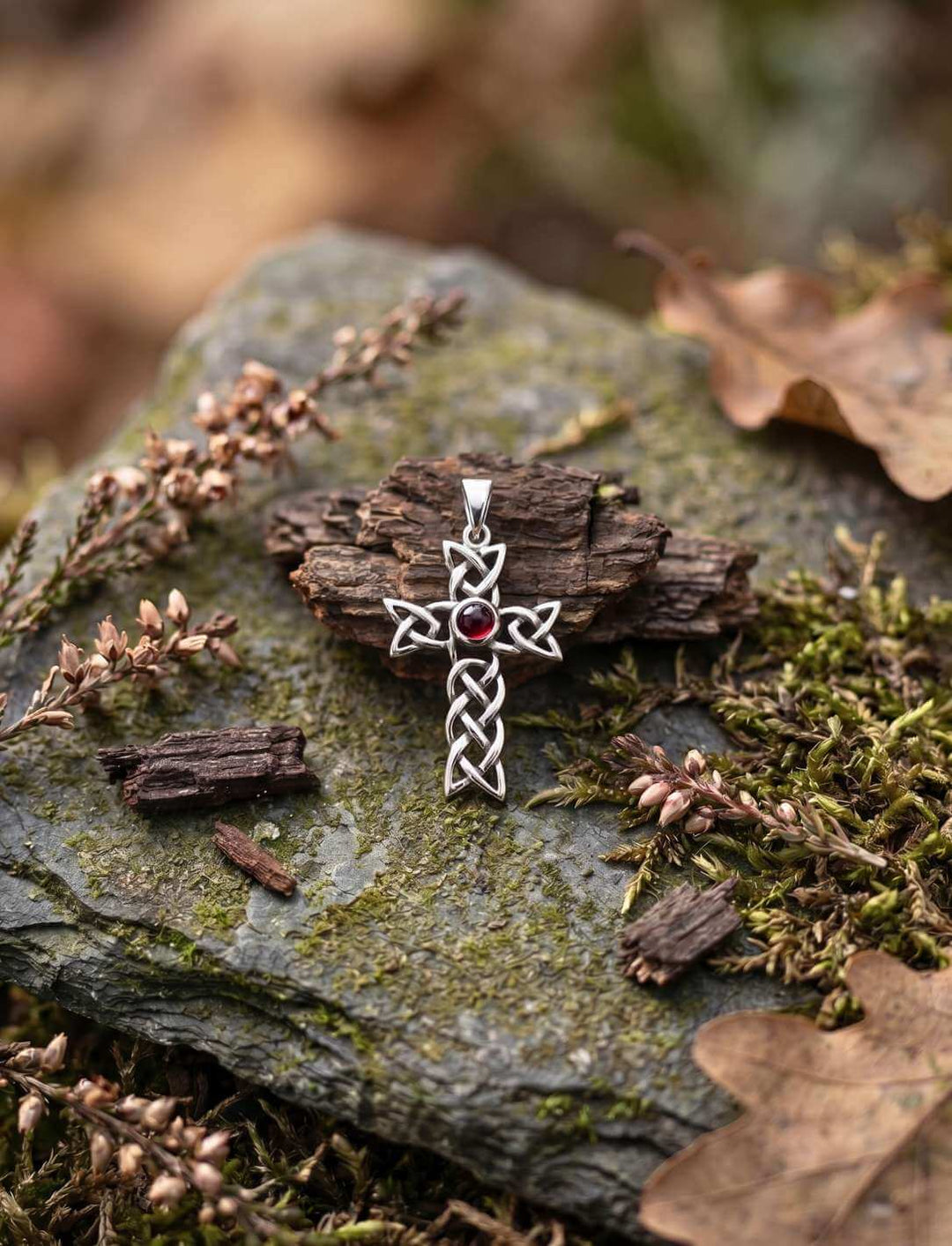 Keltisches Knotenkreuz mit Granat auf Moos und Eichenrinde