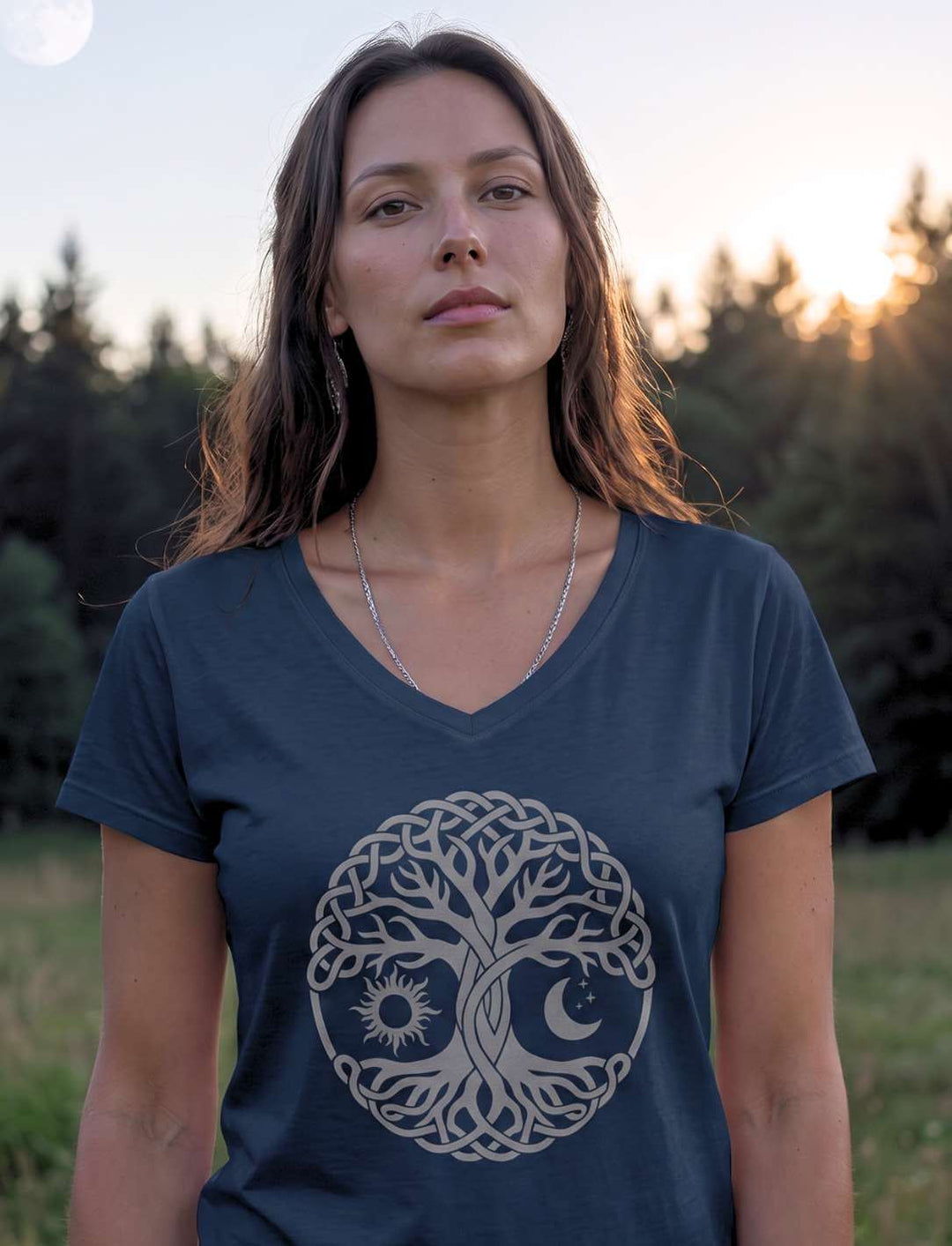 Frau im dunkelblauen Lebensbaum Shirt auf einer Wiese vor dem Waldrand
