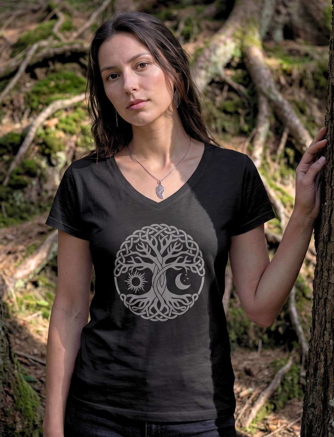 Frau im schwarzen V-Neck Shirt mit keltischem Lebensbaum vor bemoosten Baumwurzeln