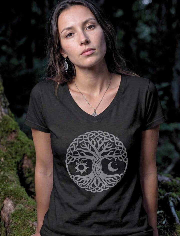 Frau im schwarzen Lebensbaum Shirt zwischen bemoosten Baumstämmen