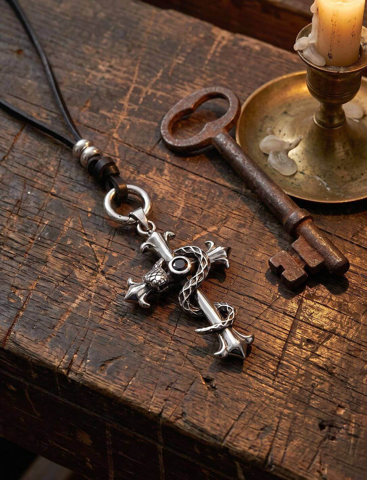 Edelstahl-Kreuz mit Schlange am Band des Waldläufers neben altem Schlüssel und Kerzenhalter auf Holztisch