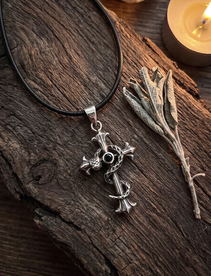 Kreuz Anhänger mit schwarzem Stein an Lederkordel auf dunklem Treibholz mit Teelicht und getrocknetem Salbei