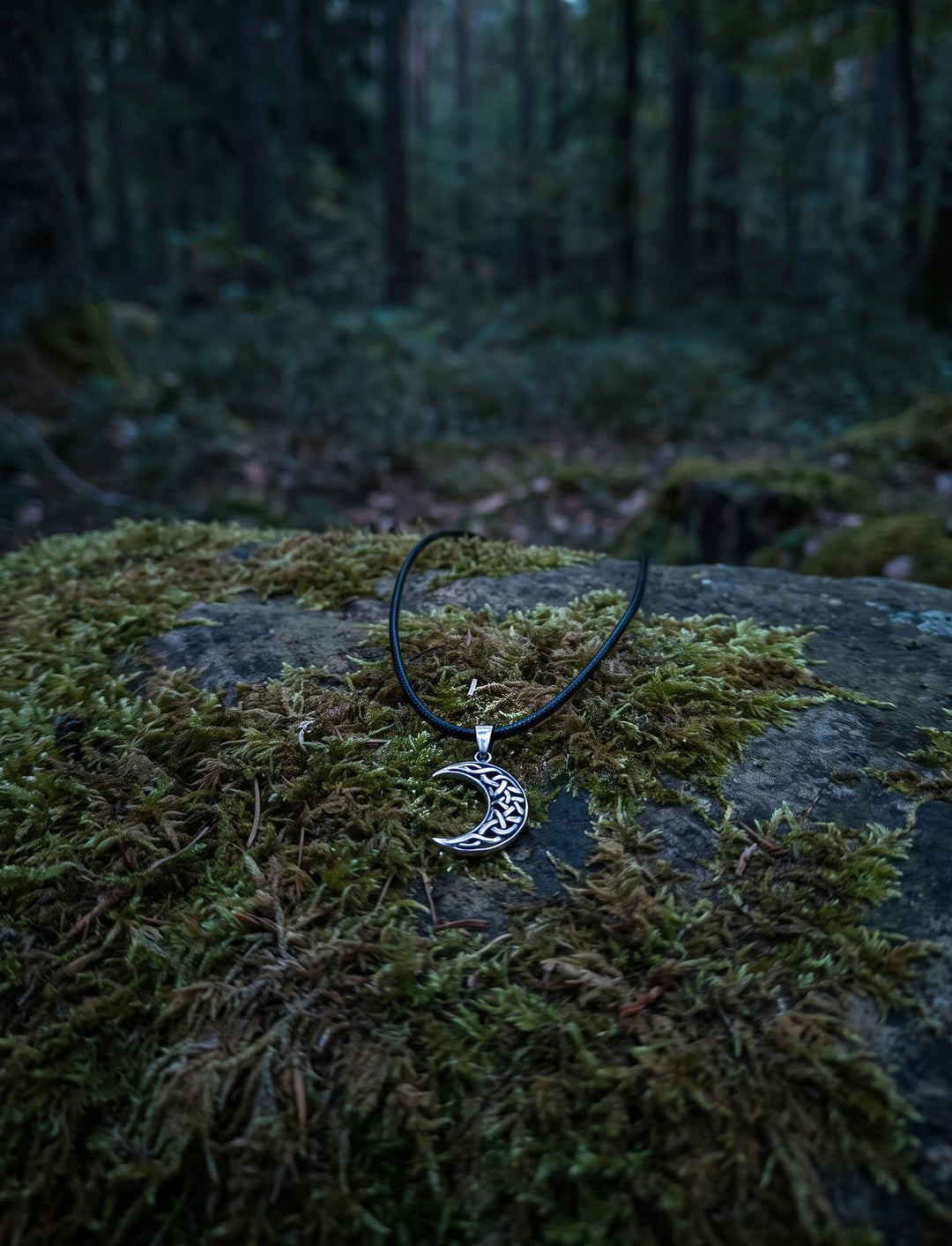 Luna Celtica: keltischer Mond Anhänger mit Knotenwerk an schwarzer Lederkordel auf einem Moosstein im dämmrigen Wald