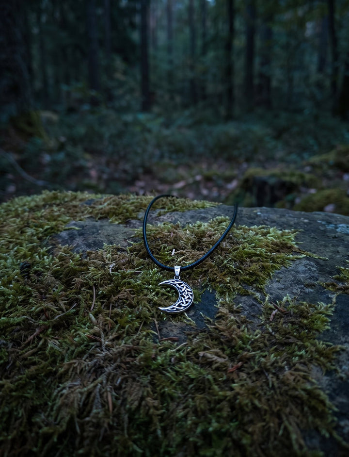 Luna Celtica: keltischer Mond Anhänger mit Knotenwerk an schwarzer Lederkordel auf einem Moosstein im dämmrigen Wald