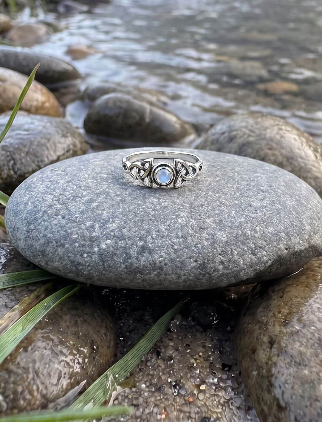 Regenbogenmondstein Ring aus 925 Silber auf einem Flusskiesel am Bachufer im Morgennebel