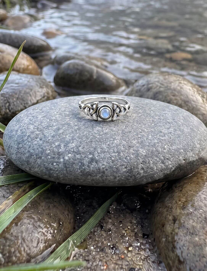 Regenbogenmondstein Ring aus 925 Silber auf einem Flusskiesel am Bachufer im Morgennebel