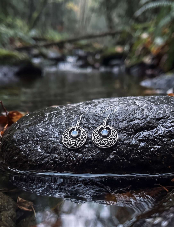Mondkreis des keltischen Knotens Silber Ohrhänger mit Regenbogenmondstein auf nassem Stein am Bach