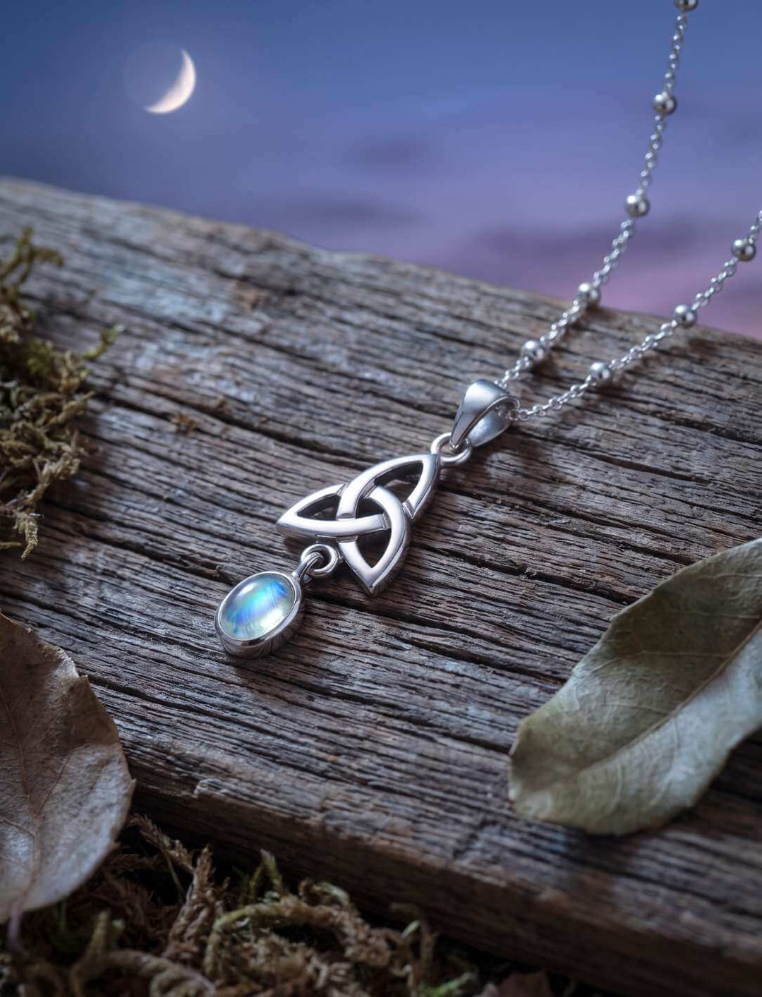 Silberanhänger mit Mondstein an Kugelkette auf Treibholz zwischen Moos und Laub
