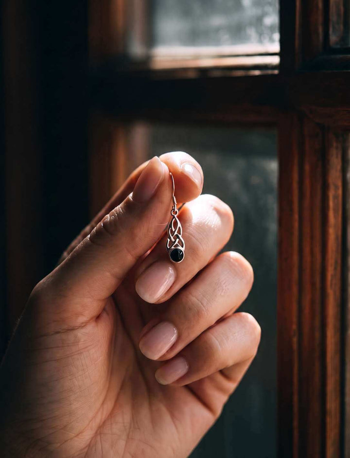 Silber Ohrhänger mit Onyx in der Hand gehalten vor Fensterlicht