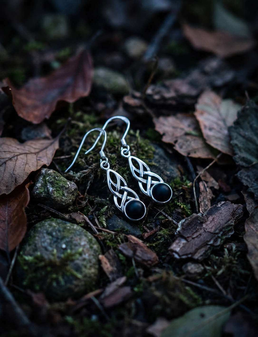 Keltische Silber Ohrhänger mit Onyx auf moosigem Waldboden
