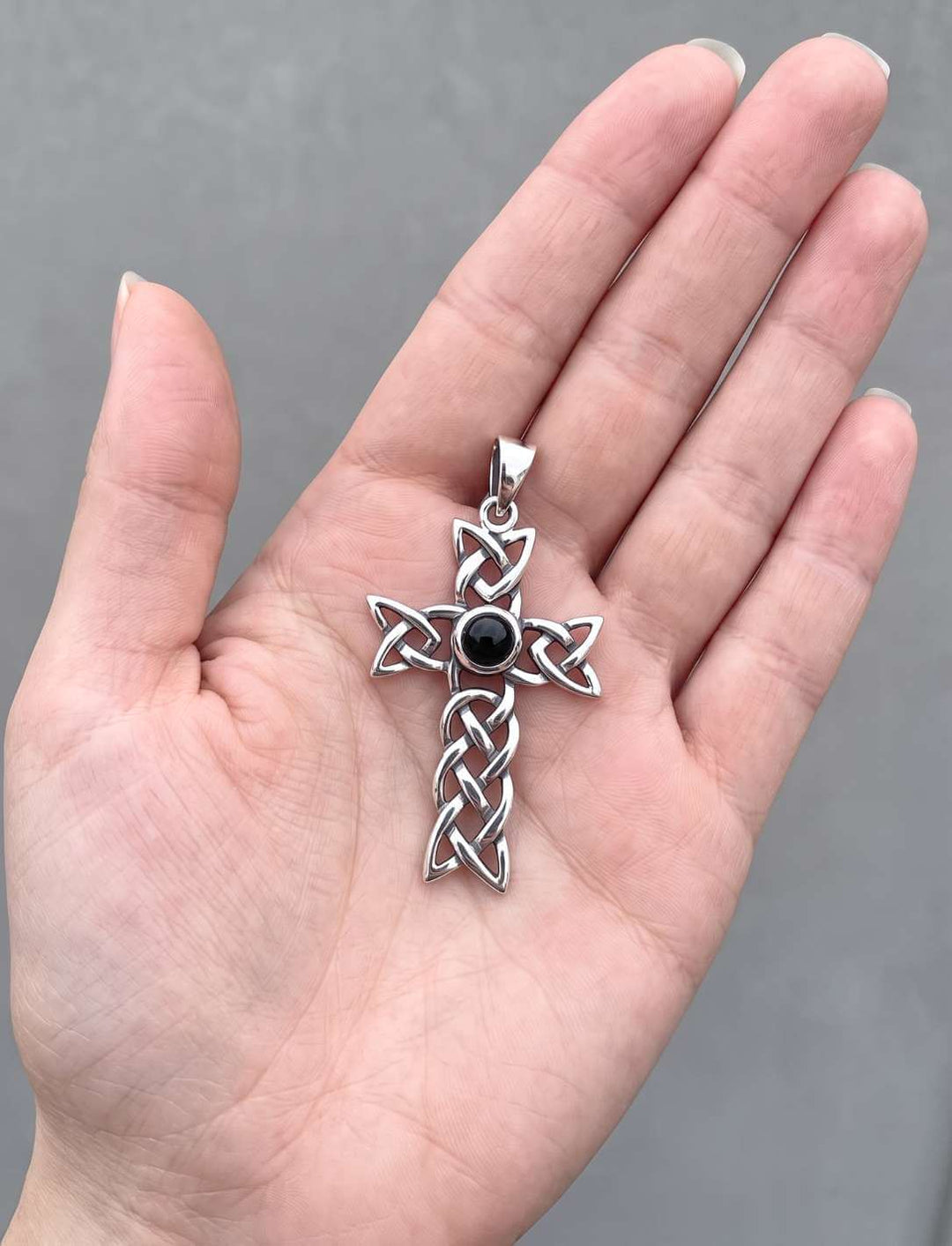 Größenvergleich: das keltische Kreuz mit schwarzem Onyx liegt in einer geöffneten Handfläche