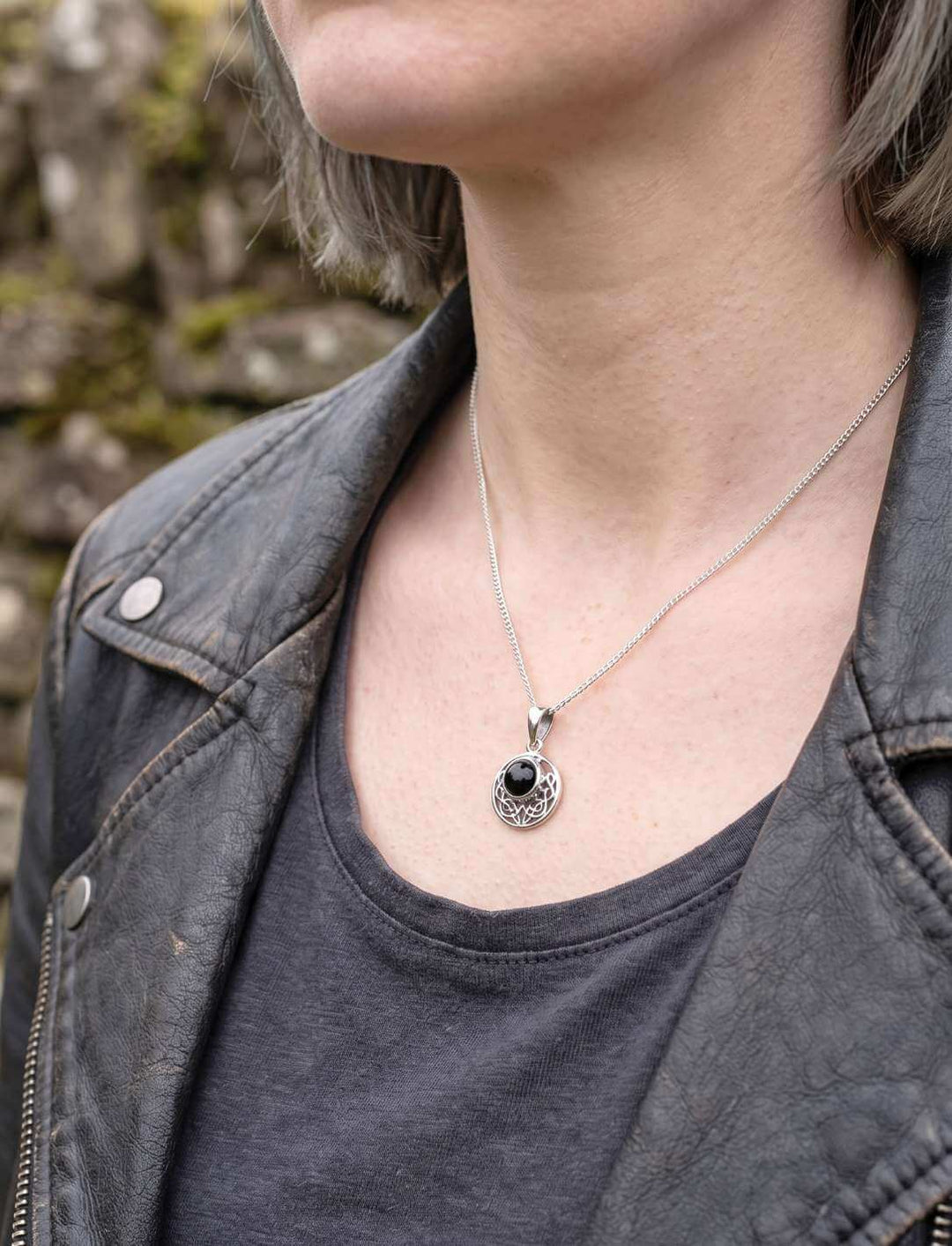 Frau in Lederjacke trägt keltischen Onyx Anhänger an feiner Silberkette