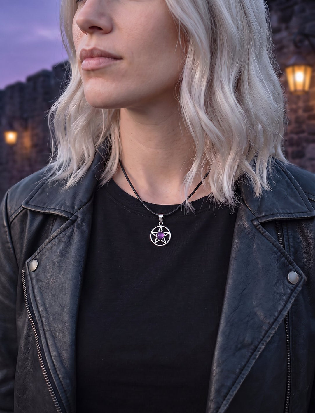 Frau mit platinblonden Haaren in schwarzer Lederjacke trägt den Wicca Anhänger mit Amethyst an einer Lederkette in der Altstadt