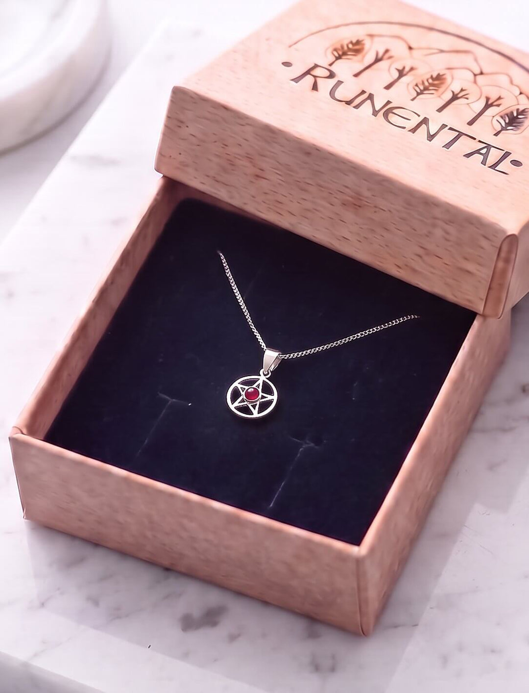 Pentagramm Kette mit Granat an feiner Silberkette in der geöffneten Runental Geschenkbox auf Marmor