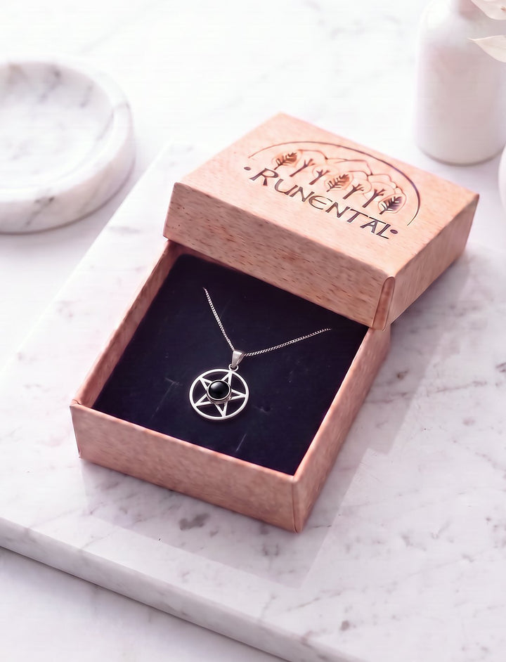 Pentagramm Kette mit Onyx an feiner Silberkette in der geöffneten Runental Geschenkbox auf weißem Marmor