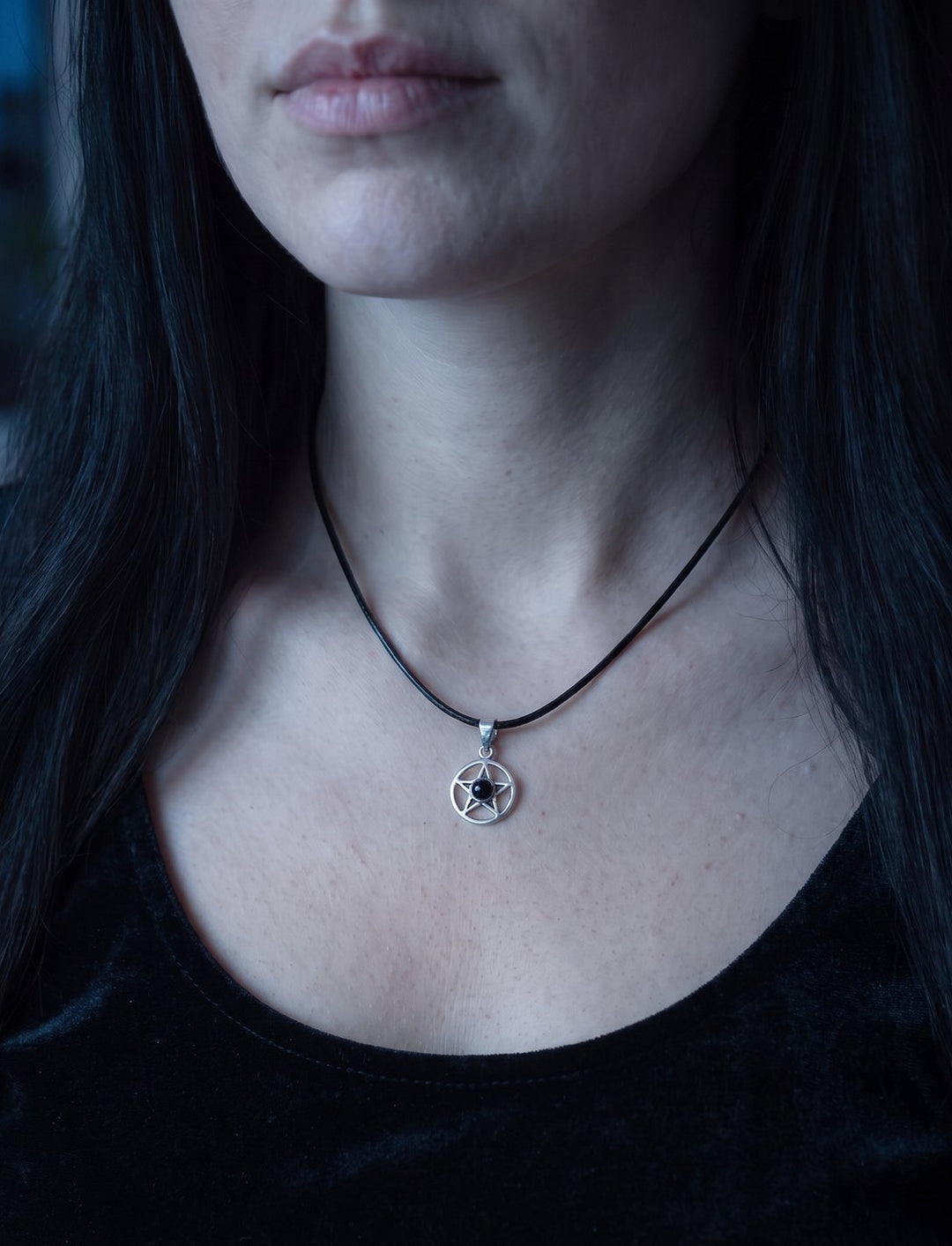 Frau mit langen schwarzen Haaren im Samtoberteil trägt den kleinen Pentagramm Anhänger mit Onyx an einer Lederkette