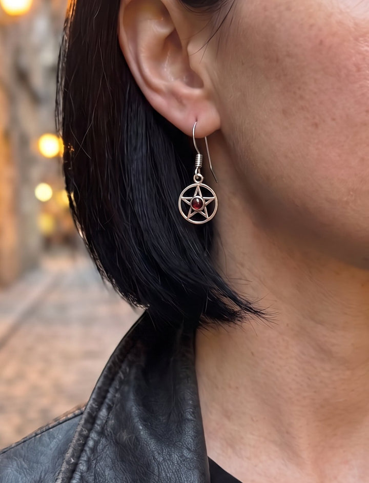 Frau in schwarzer Lederjacke mit Bob trägt Ohrringe mit fünfzackigem Stern und Granat in einer Altstadtgasse