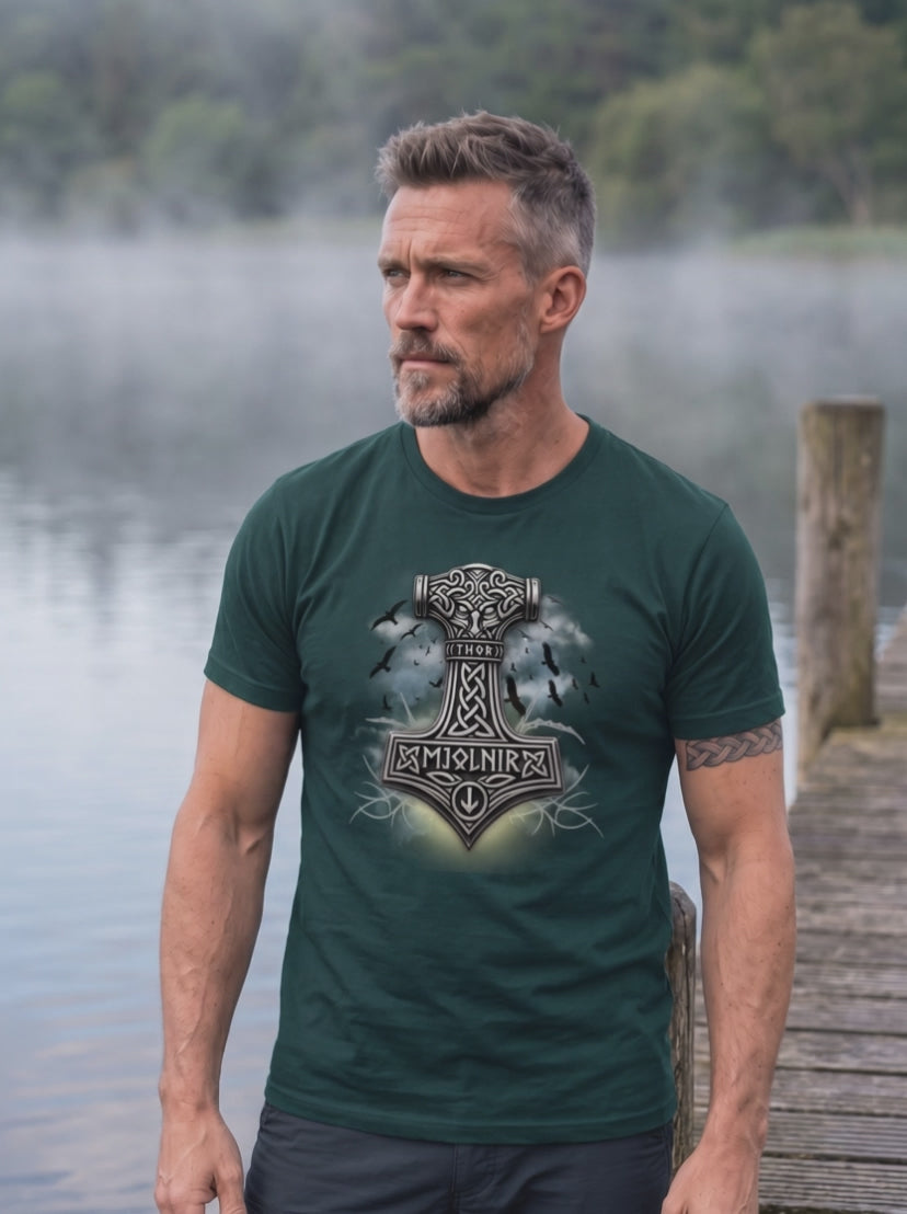 Mann in Glazed Green T-Shirt mit Thors Hammer Motiv auf einem Steg am nebligen See, Kamera umkreist ihn langsam