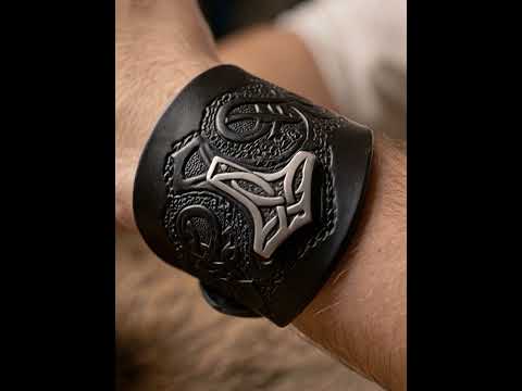 Video: Mann am Holztisch mit Trinkhorn, die Kamera fährt nah an das schwarze Thors Hammer Armband am Handgelenk heran