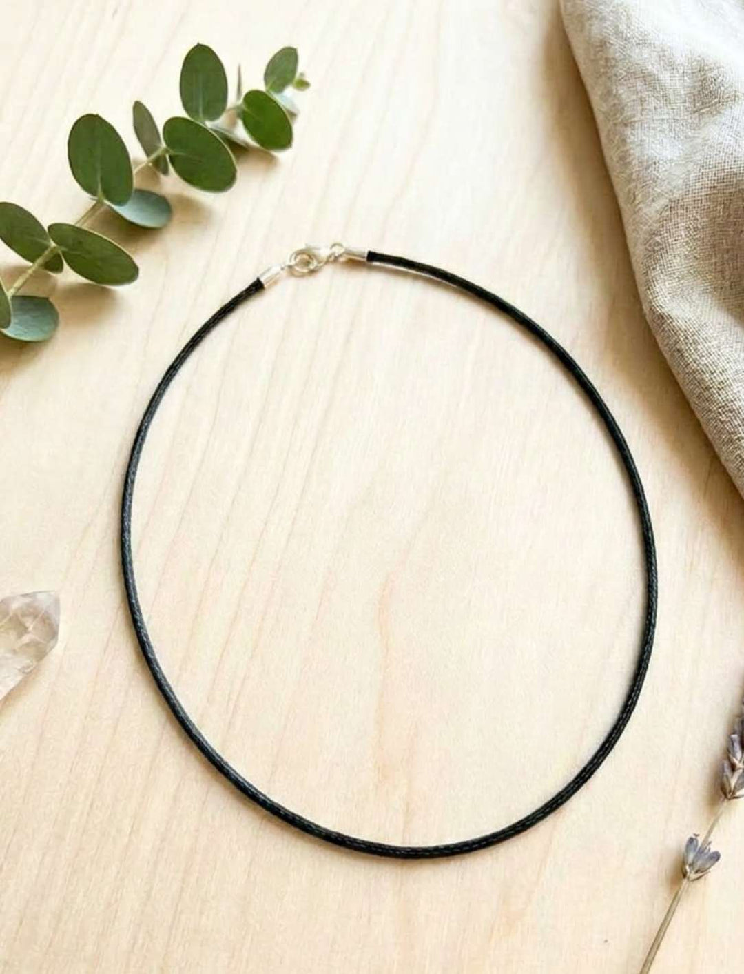 Schwarze vegane Satinkette 2mm mit 925 Silberkarabiner auf hellem Holz