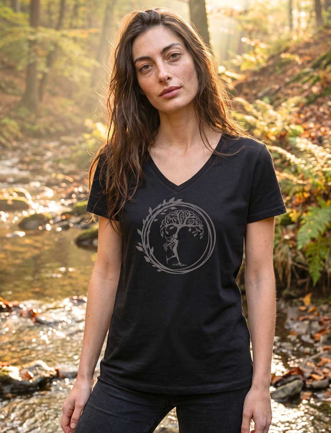 Silvaner Lebensbaum V-Neck Shirt Damen in Schwarz, getragen an einem Waldbach im Morgenlicht