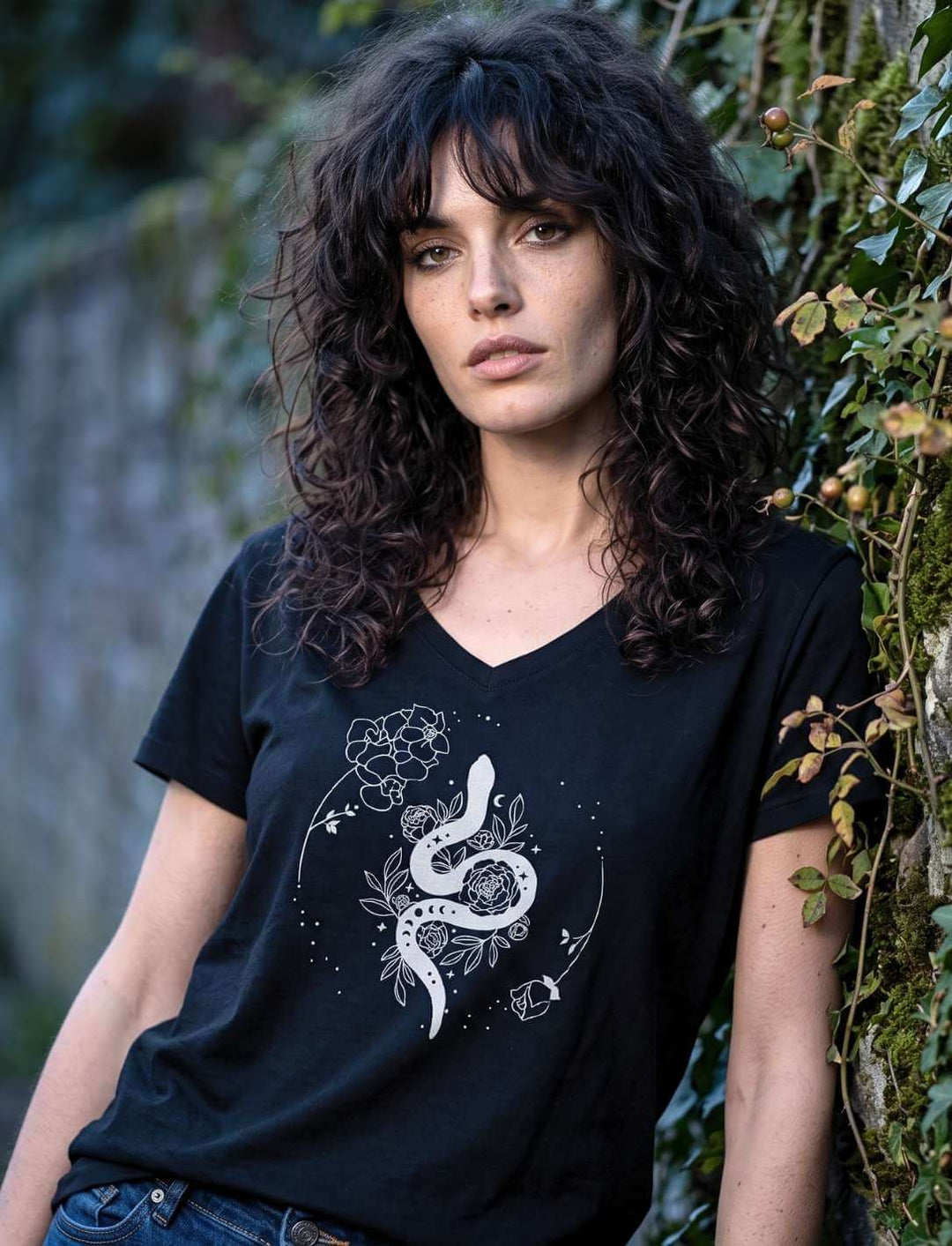 Frau im schwarzen Schlangen Shirt vor einer Efeuwand, Motiv mit Rosen und Mondkreis