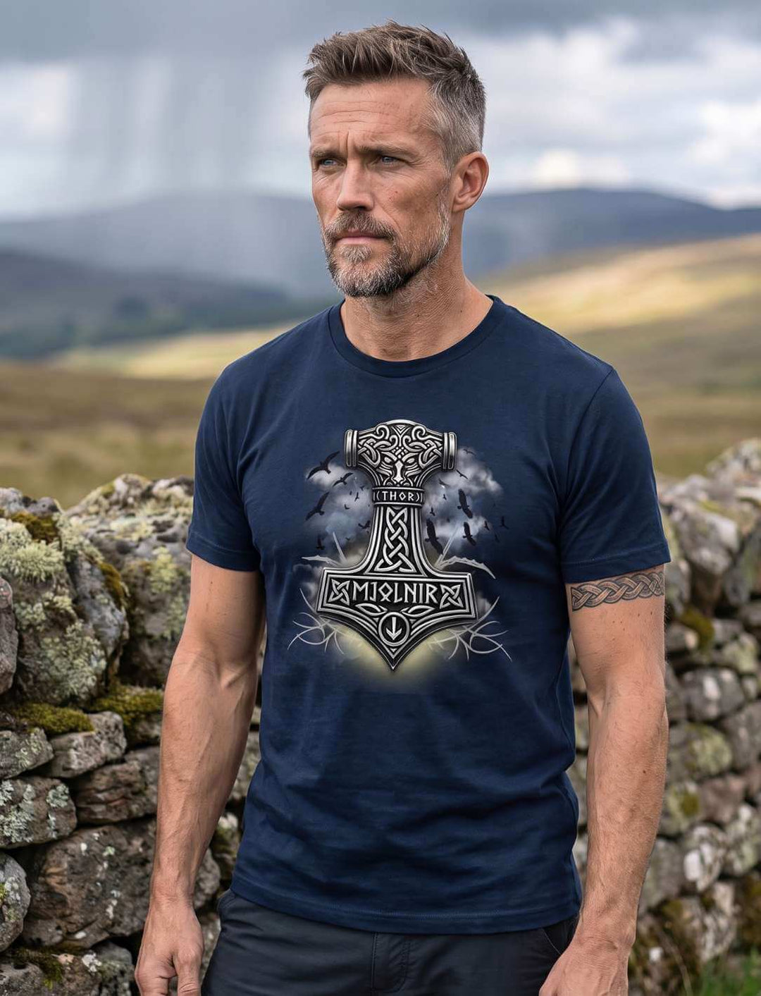 Mann in dunkelblauem T-Shirt an der Steinmauer, Gewitterwolken über dem Tal, Motiv mittig auf der Brust